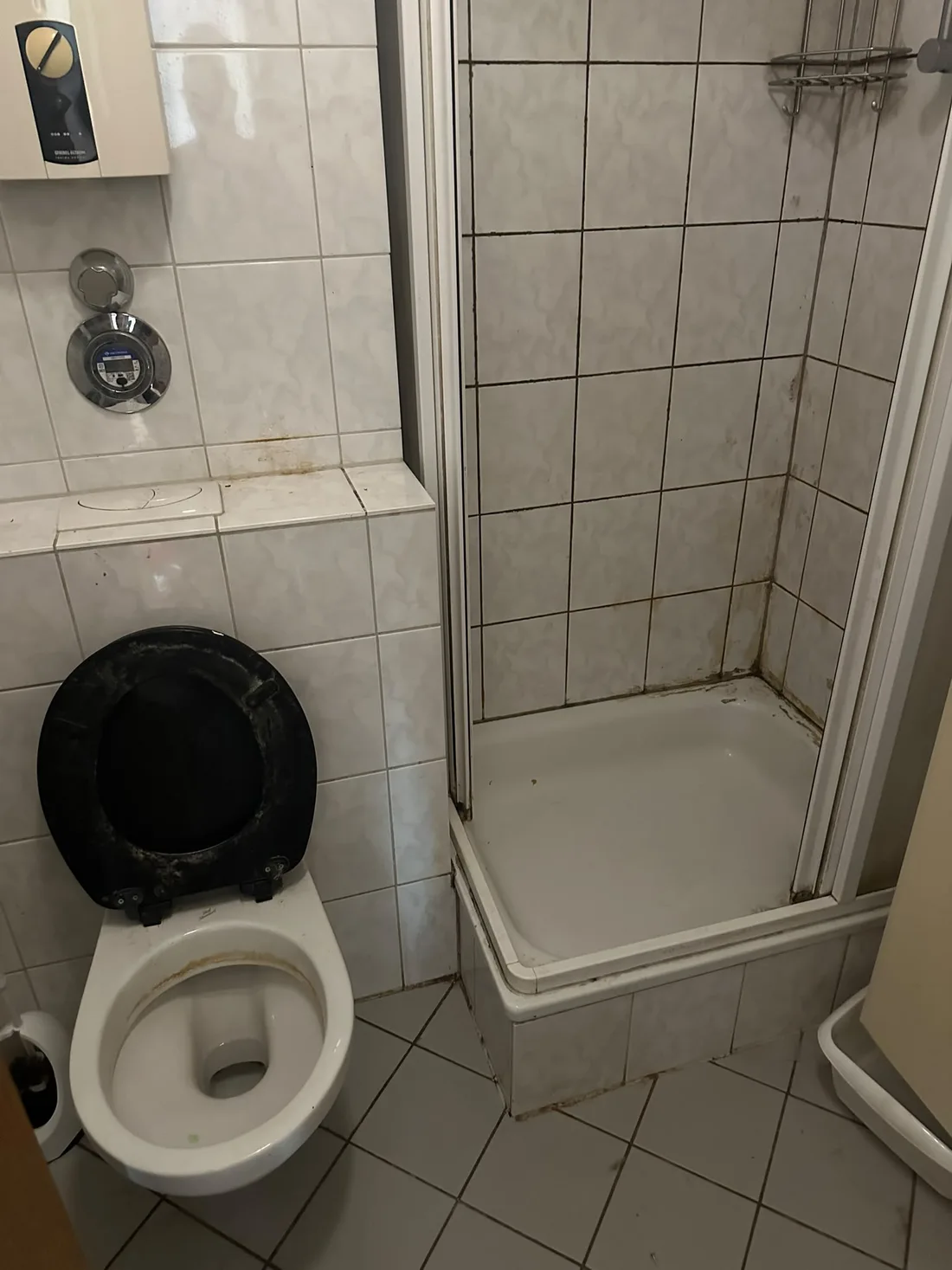Verschmutztes Bad mit WC und Dusche vor der Reinigung